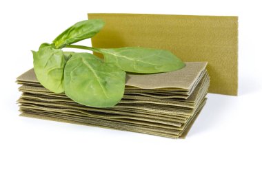 Kurutulmamış yeşil lazanya makarna örtüleri ve hamura ıspanak ilavesi. Beyaz arka planda taze ıspanak yaprakları.