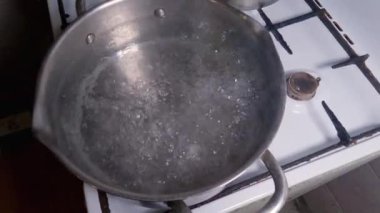 Ocaktaki paslanmaz çelik tencerede kaynar su var.