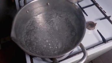 Kaynar suyla paslanmaz çelik tencereye donmuş hamur köfteleri atmak.
