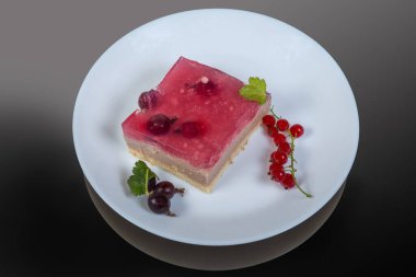 Katmanlı böğürtlenli kek, jöle kaplama ve koyu yüzeyde taze kırmızı ve siyah frenk üzümü üzümü.