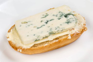 Küçük oval çörek, tereyağı ve bir tabak mavi peynirle yapılmış açık sandviç.