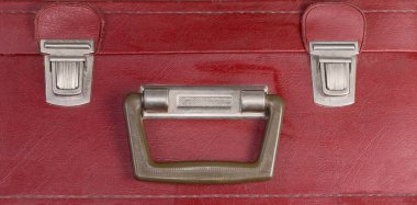 Eski kırmızı deri yerine kabuklu bavul ve iki itme mandalı, üst yakın çekim.