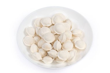 Small raw frozen dumplings round shape with meat stuffing on a white dish on a white background