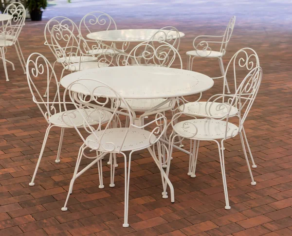 Beyaz, yuvarlak, metalik masalar ve yaz kafeteryasında kahverengi fayanslardan yapılmış, üstü açık sandalyeler.