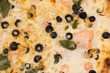 Kırmızı balıklı pizza, deniz midyesi, diğer deniz ürünleri ve zeytinler, pizza parçasının üst görüntüsü yakın plan, 
