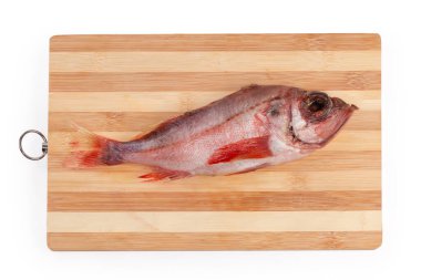 Çiğ çözünmüş tek bir kırmızı balık leşi. Okyanus levreği ya da Norveç mezgit balığı olarak da bilinir. Tahta kesme tahtasında.