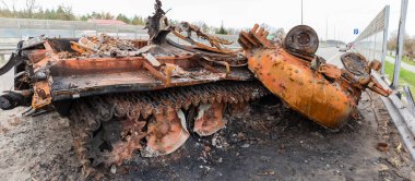 Rusya 'nın Ukrayna' yı işgali sırasında, 2022 'deki panoramik manzaralı çatışmalar sırasında otoyolda yok edilen paslı Rus savaş tankı.