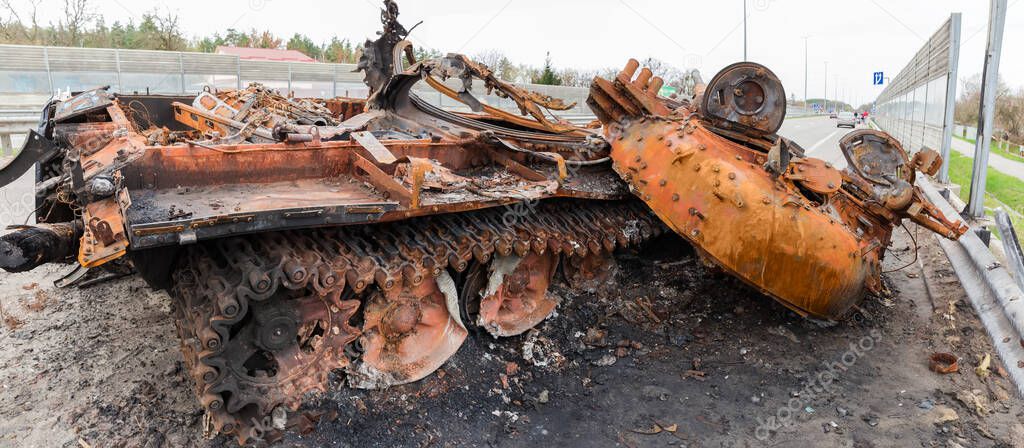 Burnt rusty Russian battle tank with torn down gun turret which was destroyed on the highway during hostilities in Russian invasion of Ukraine, panoramic view, 2022