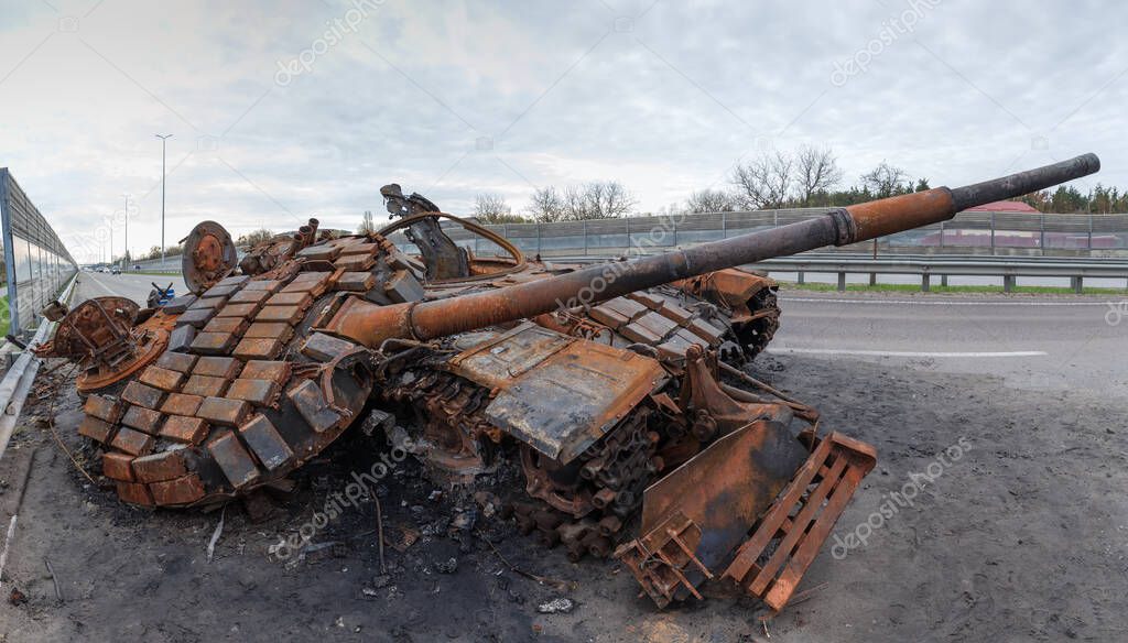 Burnt rusty Russian battle tank with torn down gun turret which was destroyed on the highway during hostilities in Russian invasion of Ukraine, 2022, panoramic view