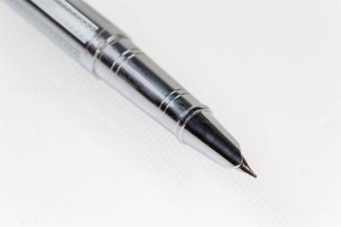 Modern metal dolmakalemin ucu seçici odak noktasında yakın plan, hafif bir yüzey üzerinde kalemin alt kısmı