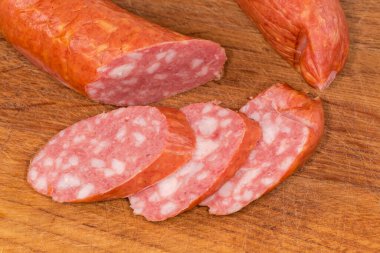 Haşlanmış sosis halkasının dilimleri ahşap bir kesme tahtasına yakın planda.