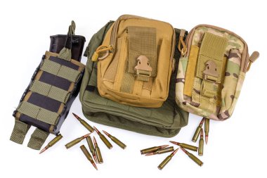 Boşaltma yeleği ya da kurşun geçirmez yelek, cepte şarjör ve beyaz arka planda saçılmış fişeklerle savaşmak için farklı askeri taktik keseler.