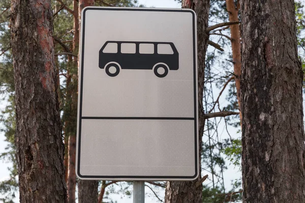 情報道路標識バス停留所いくつかの松の幹に対してパイロン上の白い背景 — ストック写真