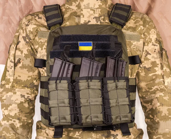 Military bulletproof vest with strapped in tactical pouches of cartridge rifle magazines wear by an Ukrainian soldier, view from the chest side