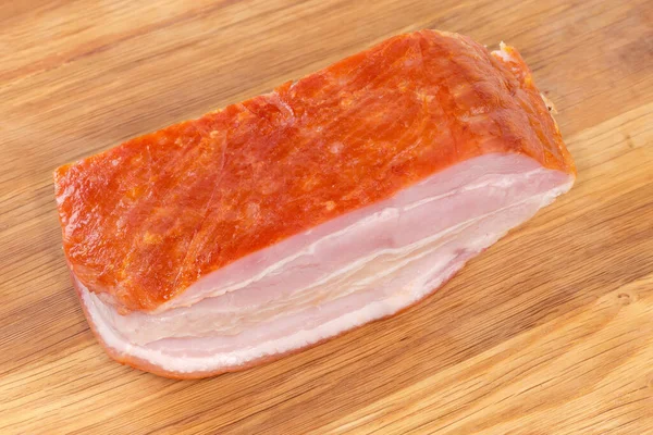 木のまな板の上の皮の上で煮込んだ豚肉の腹の部分を閉じる — ストック写真