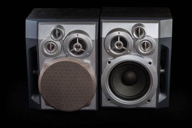 Siyah ahşap evlerde üç yönlü hoparlörlü yüksek kaliteli ev hoparlörleri. Bir tanesinin siyah arka planda dekoratif Woofer örgüsü var.