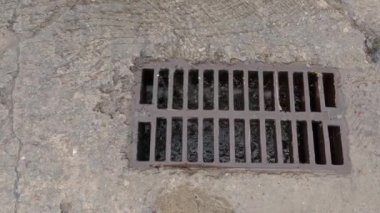 Cast iron grid of storm drain during rain close-up