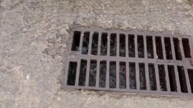 Rainwater running down to storm drain with cast iron grid