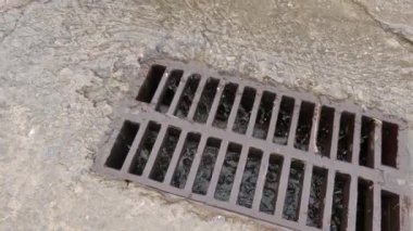 Rainwater running down to storm drain with cast iron grid