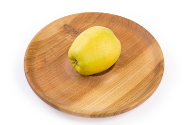 Beyaz arka planda, ahşap bir tabakta, olgun yeşil-sarı elma.