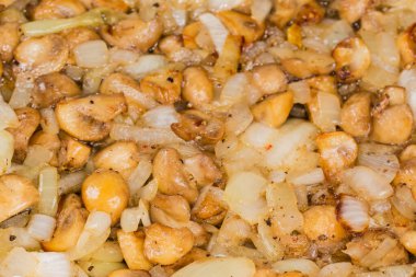 Kızarmış ve tüm küçük ekilmiş beyaz düğmeli mantarlar soğanlı, seçici odaklı yakın plan.