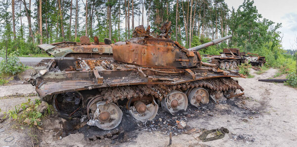 Remains of the Russian tanks and infantry fighting vehicles destroyed and burned in Russian invasion of Ukraine, 2022 and standing on a forest edge next the road, panoramic view.