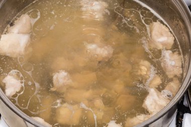 Boiling of the meat broth in a stainless steel pot during the cooking close-up
