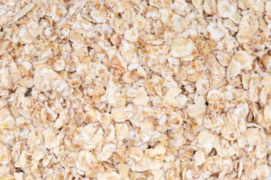 Evenly sprinkled raw thin-rolled oats close-up, background