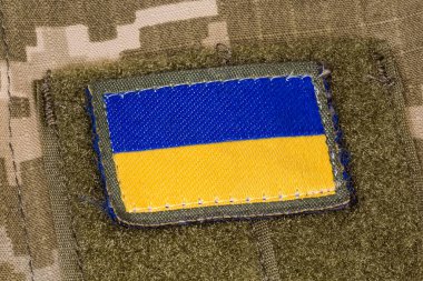 Textile Ukrainian flag sticker with hook-and-loop fastener fixed on a military camouflage uniform close-up