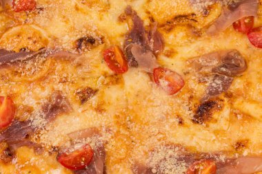 Surface of the pizza with ham and cherry tomatoes, top view of pizza fragment, background