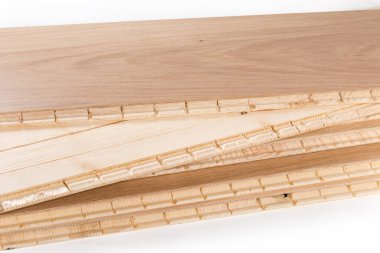Stack of the three-layer engineered wood flooring boards with white oak face layer and pine core layer, fragment of the glue-less locking joint system close-up