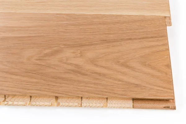 Connected three-layer engineered wood flooring boards with white oak face layer, pine core layer and glue-less locking joint system, fragment close-up on a white background