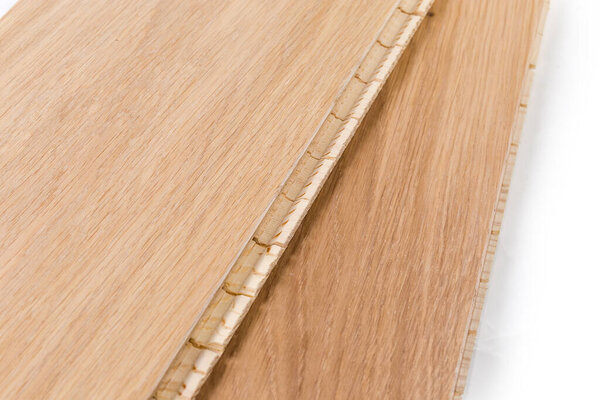 Three-layer engineered wood flooring boards with white oak face layer, pine core layer and glue-less locking joint system, locking joint system close-up in selective focus, fragment 
