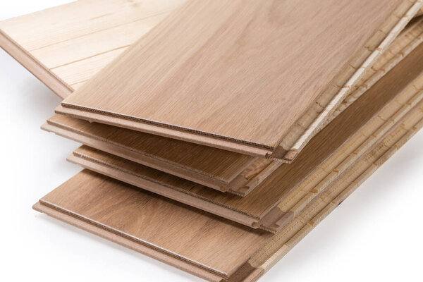 Stack of the three-layer engineered wood flooring boards with white oak face layer, pine core layer and glue-less locking joint system, fragment close-up
