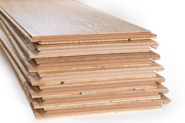 Stack of the three-layer engineered wood flooring boards with white oak face layer, pine core layer and glue-less locking joint system, butt-end parts close-up in selective focus