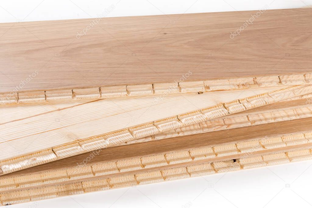Stack of the three-layer engineered wood flooring boards with white oak face layer and pine core layer, fragment of the glue-less locking joint system close-up