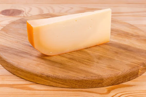 一块半硬奶酪 作为大型奶酪轮的一部分 在一个乡村桌子上的圆形切割板上以分段的形式出现 — 图库照片
