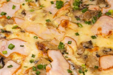 Jambonlu ve diğer et ve mantarlı pişirilmiş pizza, seçici odak noktasında yakın plan.