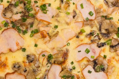 Jambonlu ve diğer et ve mantarlı pişirilmiş pizza, yakın çekimin üst görüntüsü.