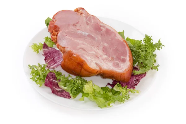 白い背景に白い皿の上に異なるレタスの葉の上に豚肉の煮たスモークハムのホットの半分 — ストック写真