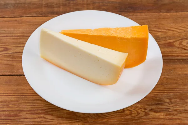 两片不同的半硬奶酪 在乡村餐桌上的白盘上呈片状 — 图库照片