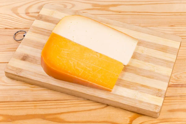 两个不同的半硬奶酪 在一个乡村桌子上的木制竹子切菜板上分割成几段 — 图库照片