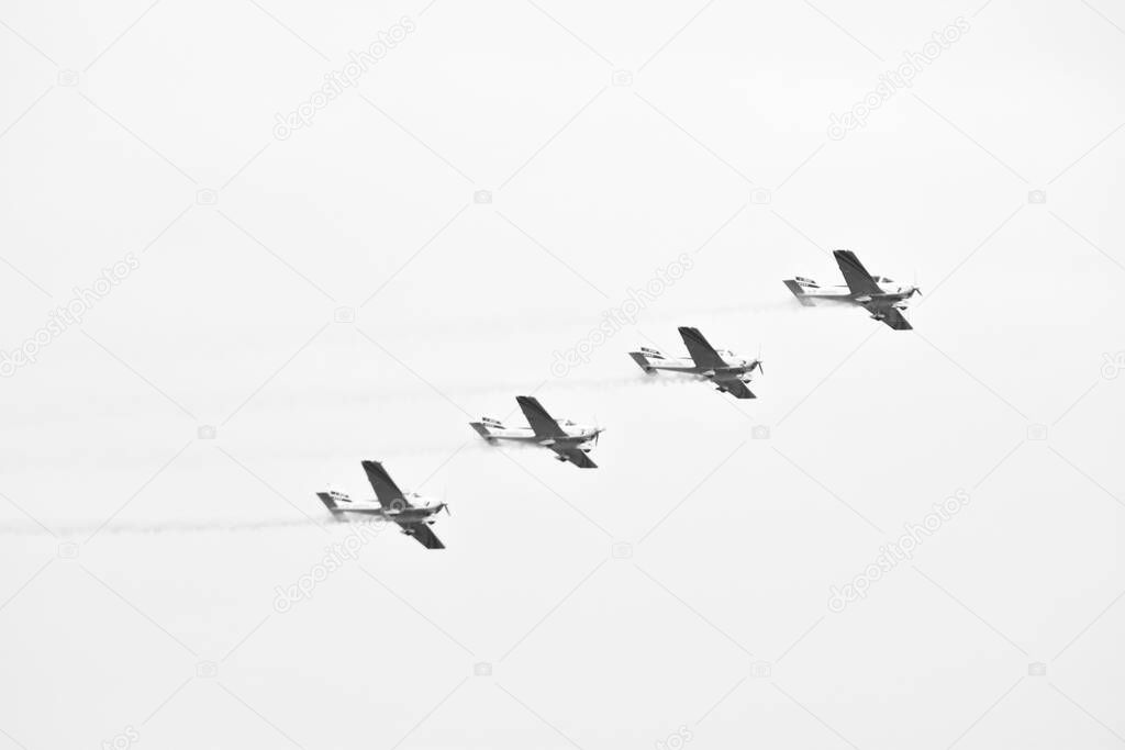 Ancient plane flying in oblique line with grey sky as background