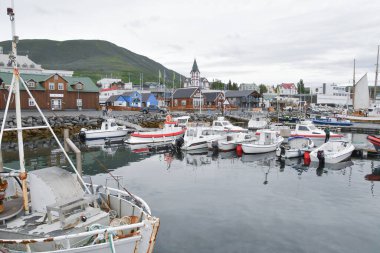 Limanda demirli tekneler, Husavik köyü kilisesi ve İzlanda 'da bir zemin olarak dağları var.
