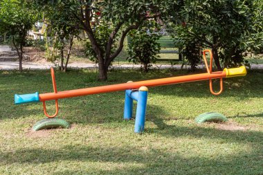 Yazın bahçedeki çocuk parkına portakal boyasıyla boyanmış metalik bir salıncak.