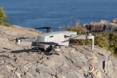 The Gray unmanned aerial vehicle with four propellers and blades is on the orange stone background