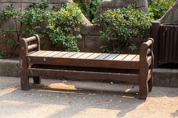 公园里的人行道旁边 站着一个漆成褐色的古旧漂亮的木制长椅 — 图库照片