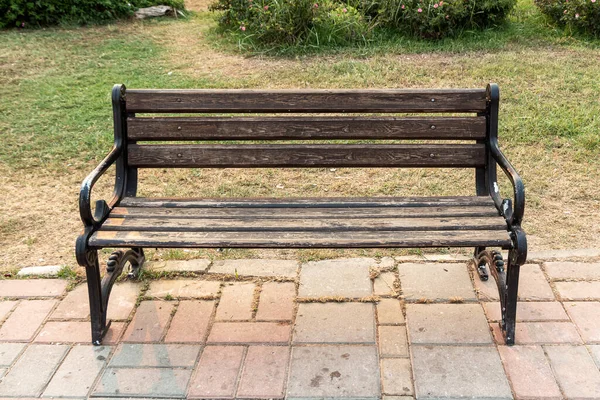 公园里的人行道边 站着一条黑色锻铁腿 漆成褐色的古旧漂亮长椅 — 图库照片