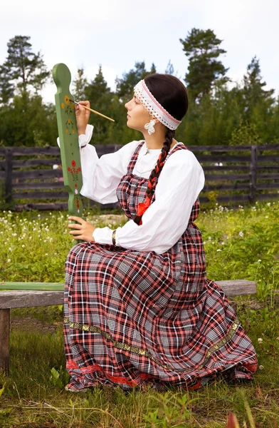 Girl in national costume paints a spinning wheel — Stock Photo, Image