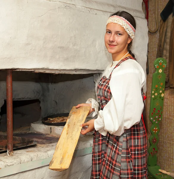 Chica en traje nacional prepara la comida en la estufa —  Fotos de Stock